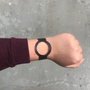 A paper watch on a wrist with a background of concrete.