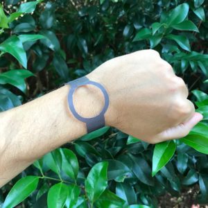 A paper watch on a wrist with a background of leaves.