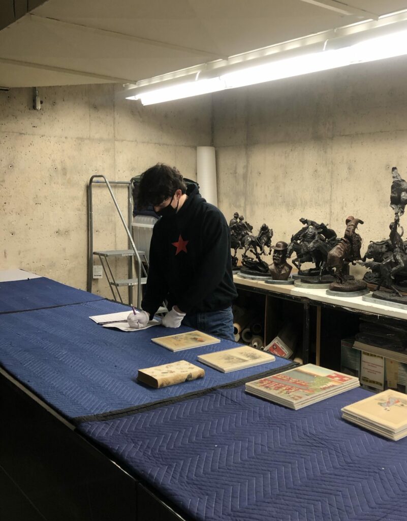there is a man that is standing over a table with some books on it