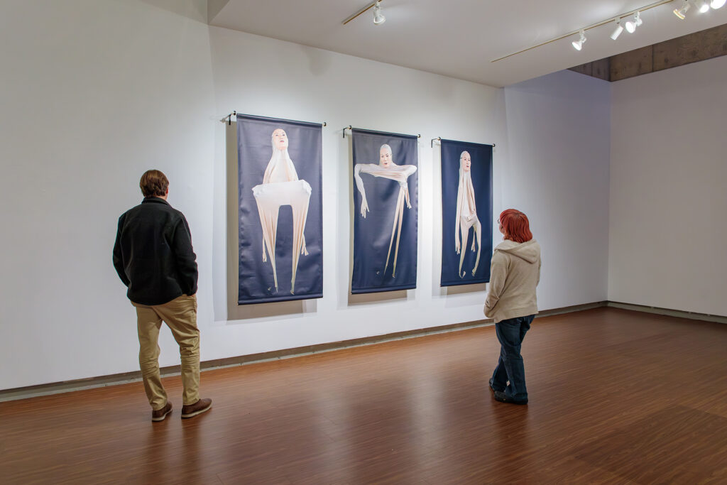 there is a man and a woman standing in front of three paintings